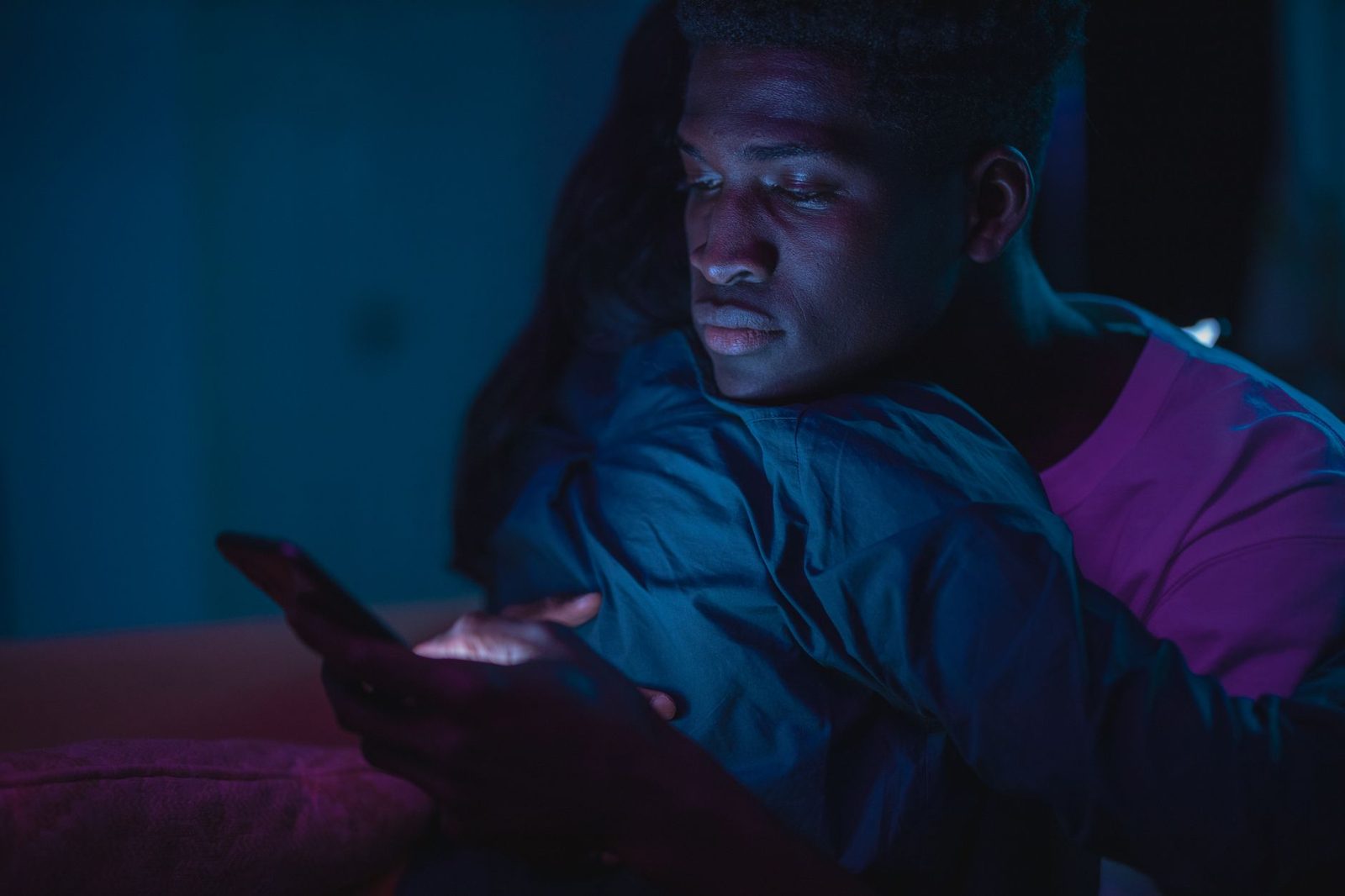 Young man looking at his phone in the dark